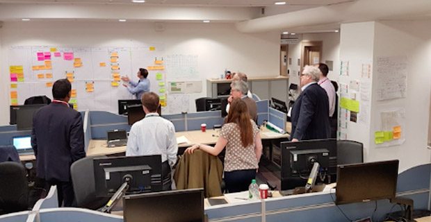 Group in an office looking at whiteboard with post it notes on