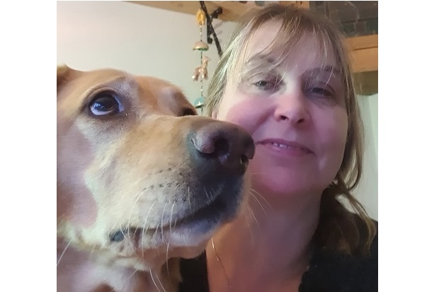 On the right, a close up of a dog's face, and on the left a lady with long hair, smiling at the dog.