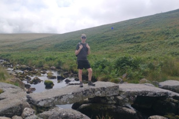 Tom Metcalf standing on rock over a stream with hills in the background