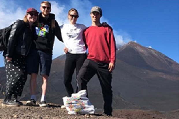 Four people standing with a mountain in the background.
