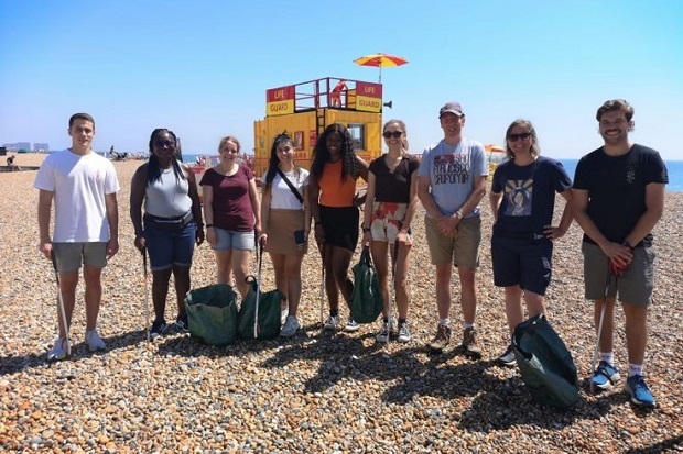 A group of people standing on a beach, with blue sky in the background.