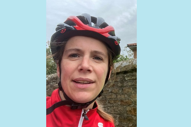 A lady wearing a cycle helmet and red jacket.