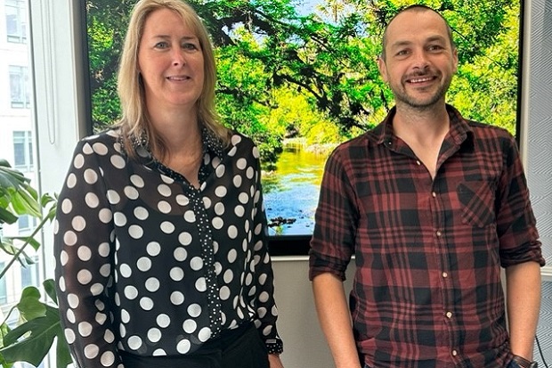 On the left a lady, with long fair hair and wearing a black and white spotted blouse, on the right a man with short dark hair and a beard wearing a black and red checked shirt.