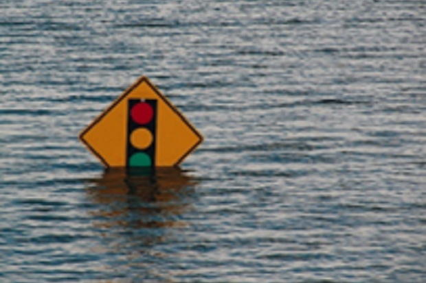 An image of a stop sign submerged in floodwater.]